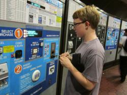 Teenage boy using DC Metro fare machine.